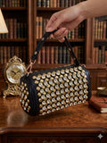 Crystal rhinestone barrel bag in black and gold on wooden table