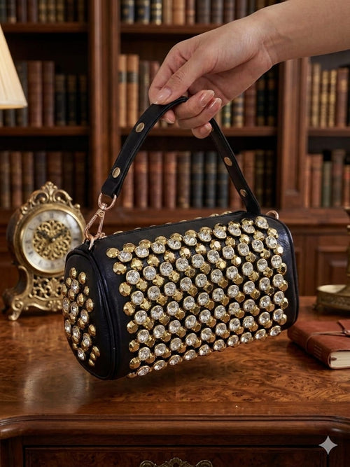 Crystal rhinestone barrel bag in black and gold on wooden table