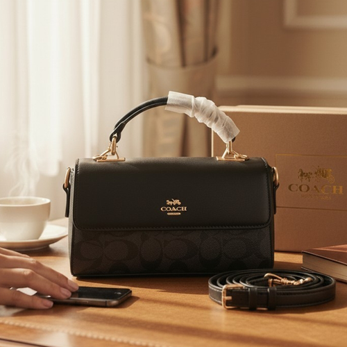 Coach Eliza foldover top handle bag black on wooden table showing detachable crossbody strap