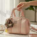 Miu Miu Arcadie bowling bag blush pink on white table with charm cluster and detachable crossbody strap