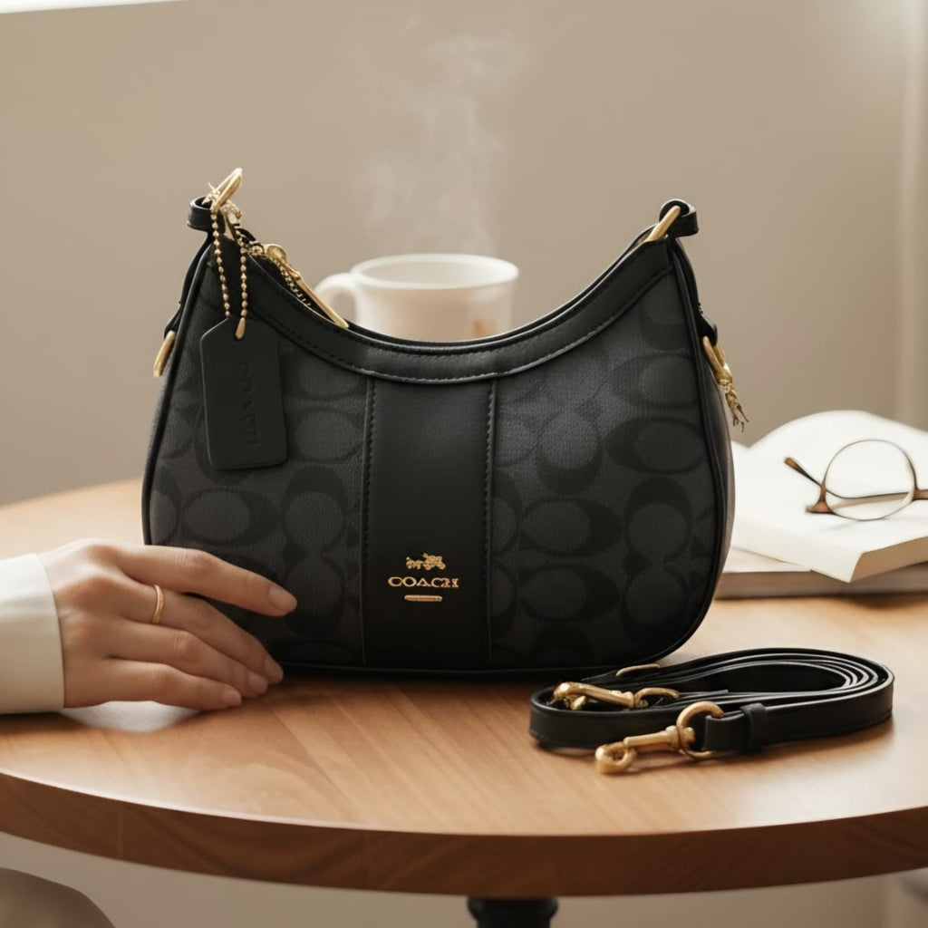 Coach Payton hobo bag black signature canvas on wooden table with coffee mug book and glasses