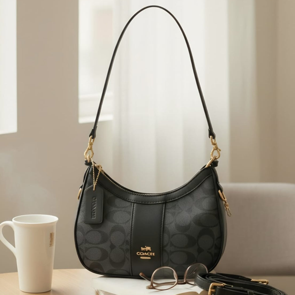 Coach Payton hobo bag black signature canvas on wooden table showing single shoulder strap and detachable crossbody strap