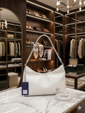 Coach Cassy hobo bag in ivory white on marble counter in luxury boutique